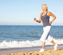 Senior Woman In Fitness Clothing Running Along Beach